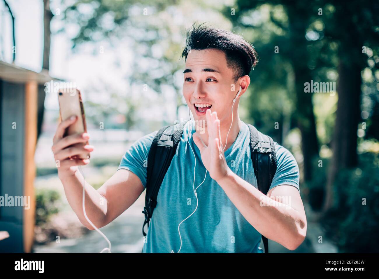 un jeune homme heureux qui marche dans la rue et utilise un téléphone portable Banque D'Images