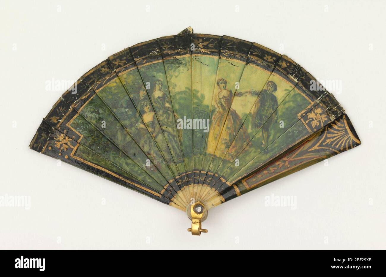 Ventilateur bris miniature. Ventilateur brusé miniature. Bâtonnets d'ivoire peints et dorés. Obverse: Paysage avec des figures dans des tons de vert et d'or. Inverse : ruines dans un paysage. Les protections sont peintes en noir, rouge et vert. Ruban de papier. Le rivet est réglé avec une pierre. Étrier en métal doré. Banque D'Images