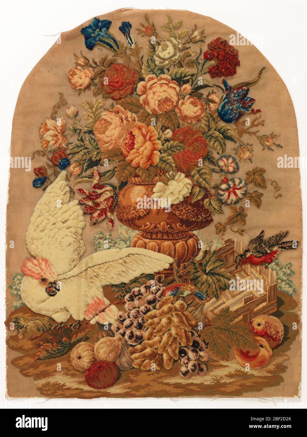 Pare-feu. Panneau d'un écran de firesscreen avec broderie dans le travail de Berlin élevé. Une grande urne avec des fleurs et des fruits a travaillé dans de nombreuses couleurs, avec un petit oiseau rouge à droite et un grand cafard blanc à gauche. Banque D'Images