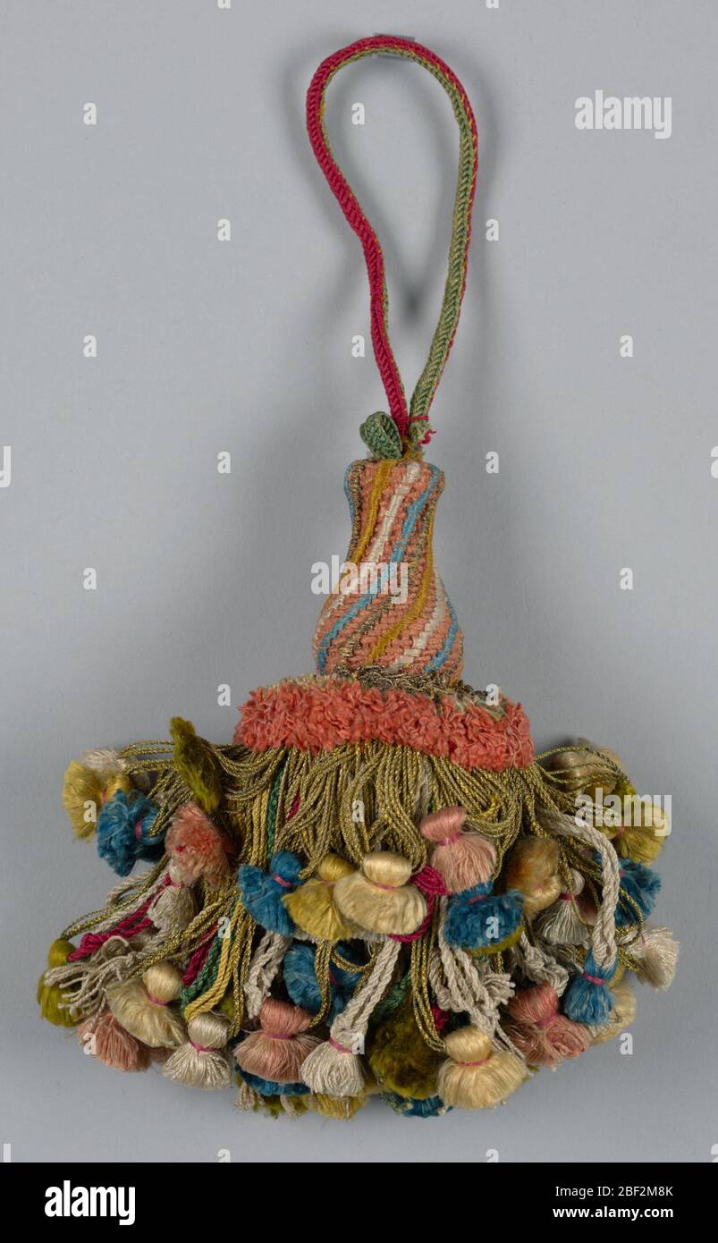 Pampille. Jupe en soie colorée et fils métalliques avec glands roses, blancs, bleus, verts et jaunes. Col en soie à franges et fils métalliques bouclés. La tête est en forme de vase avec une couverture de rayures spirales dorées, jaunes, blanches et bleues sur un sol rose. Banque D'Images
