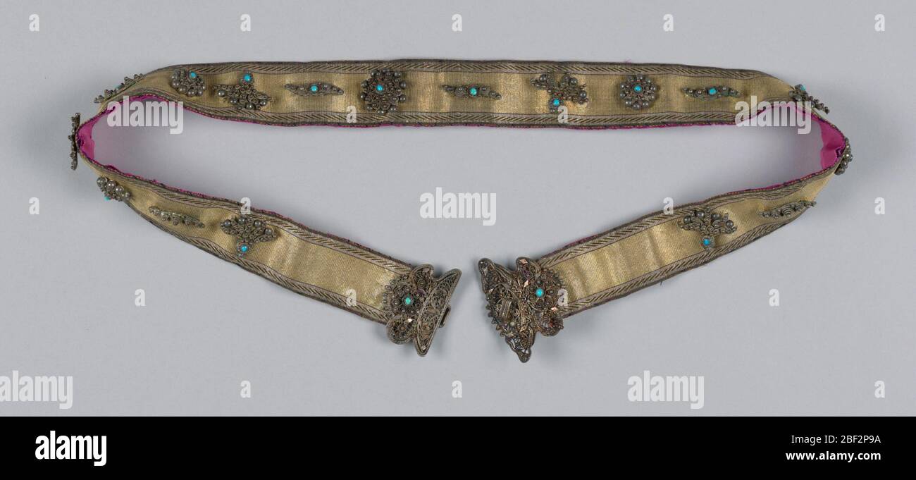 Courroie. Ceinture pour femme en ruban or et noir avec boucle en filigrane argent décorée de turquoise et d'autres matériaux. Doublé de soie magenta. Banque D'Images