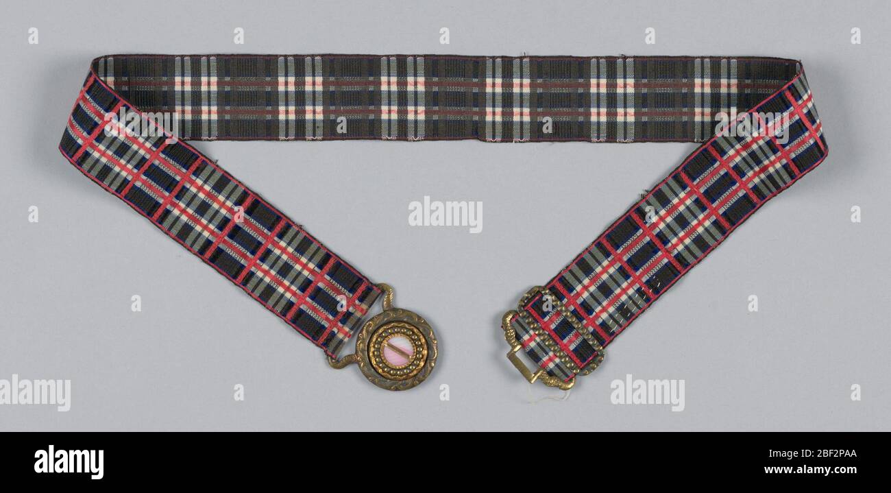 Courroie. Ruban de plaid noir, blanc, rose et bleu avec une boucle de laiton argenté et un ornement de coquille rose et blanc. Banque D'Images