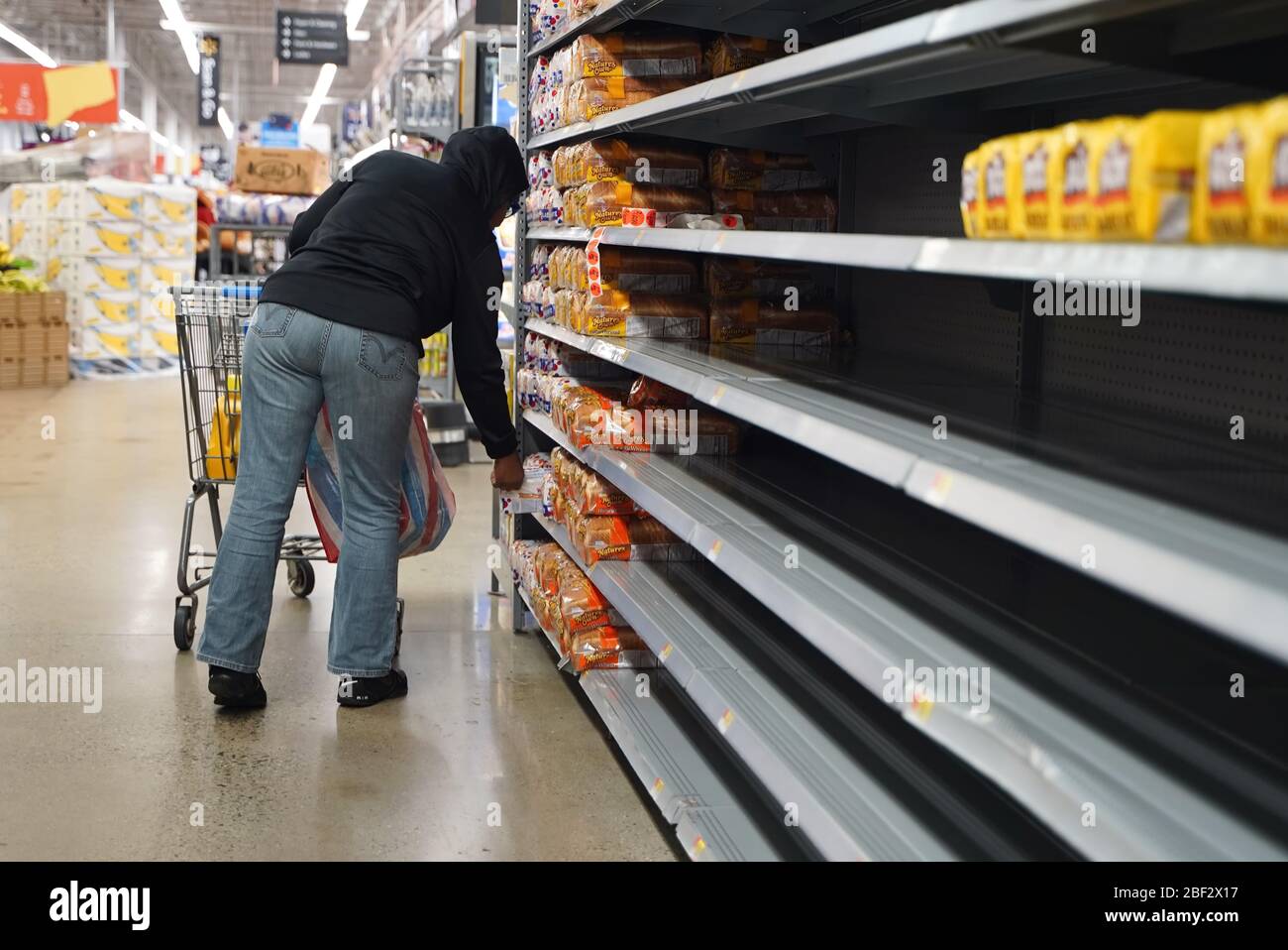 Cromwell, CT / USA - 20 mars 2020: Afro-américain shoppers choisit un pain à partir de étagères vides Banque D'Images