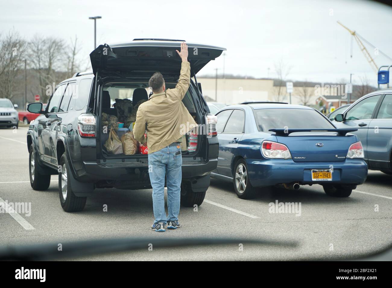 Groton, CT / USA - 4 avril 2020: L'homme caucasien charge des provisions dans son tronc Banque D'Images