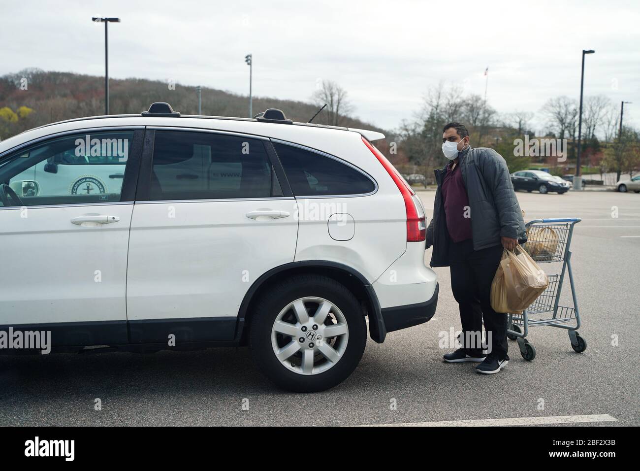 Groton, CT / USA - 4 avril 2020: L'homme indien charge des provisions dans son tronc Banque D'Images