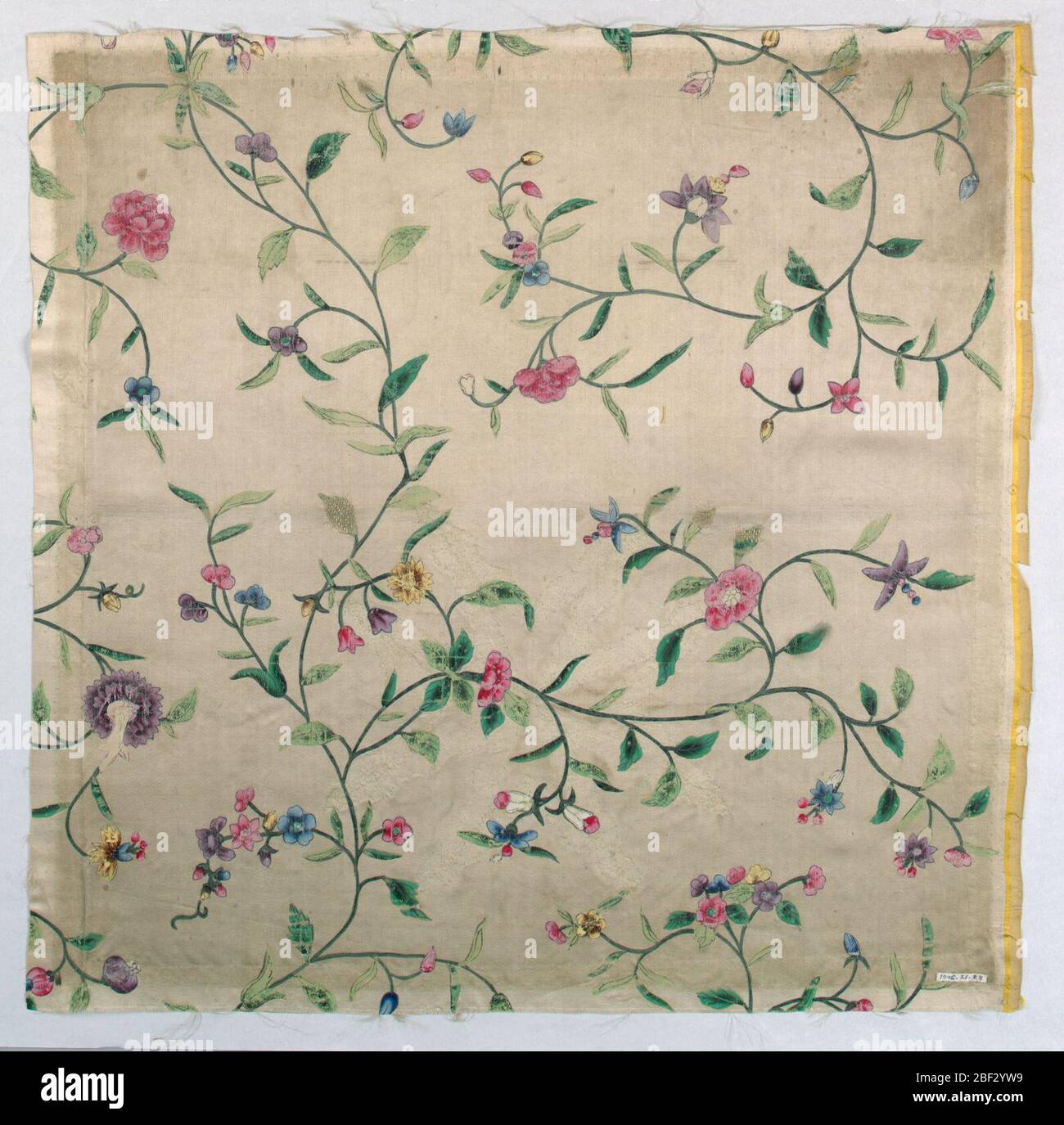 Fragment. Terrain blanc avec une conception de tiges en serpentine fines avec des tiges latérales courant horizontalement sur la pièce, avec de petites fleurs, des bourgeons et des baies. Peint en vert, rouge, bleu, jaune et violet. Banque D'Images