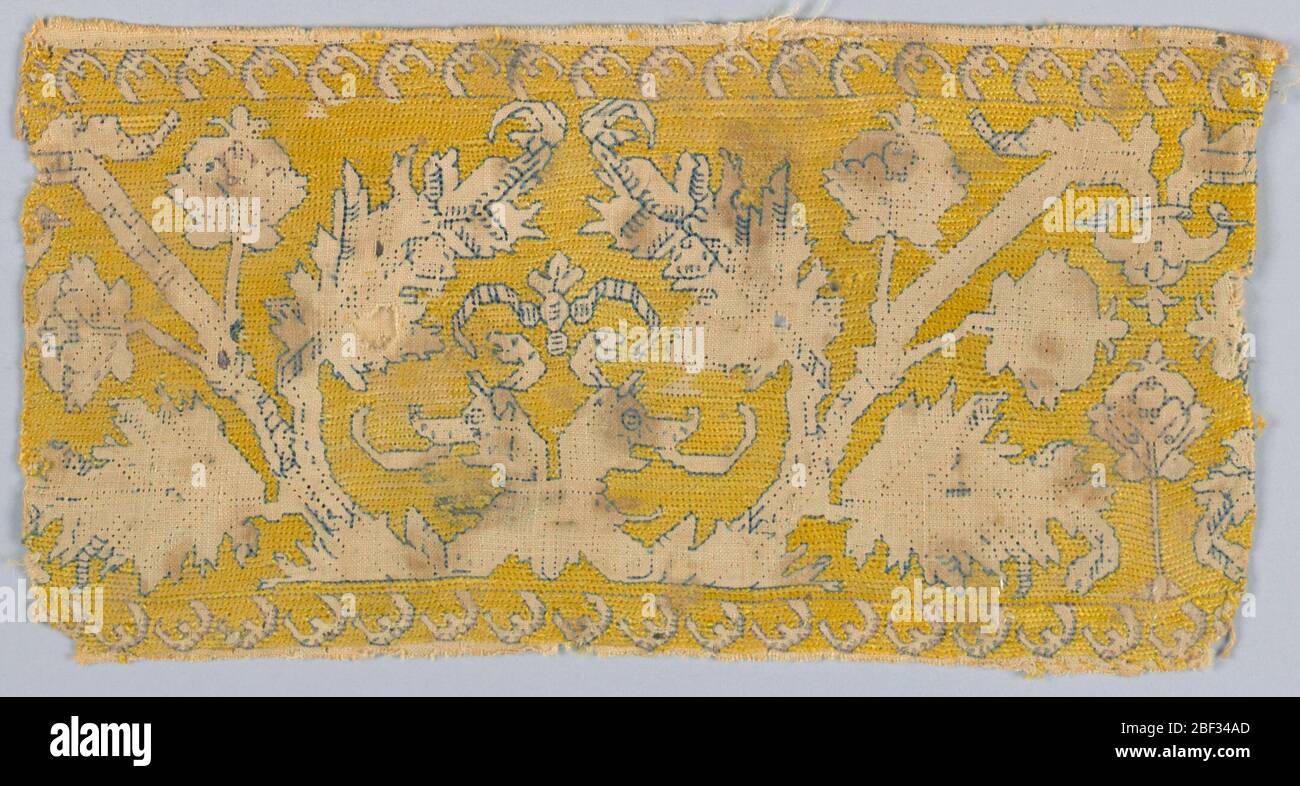 Fragment. Fragment textile. Bande représentant un motif symétrique d'un dragon à double tête et d'arbres bordés de soie bleu foncé dans la réserve sur un fond jaune brodé. Banque D'Images