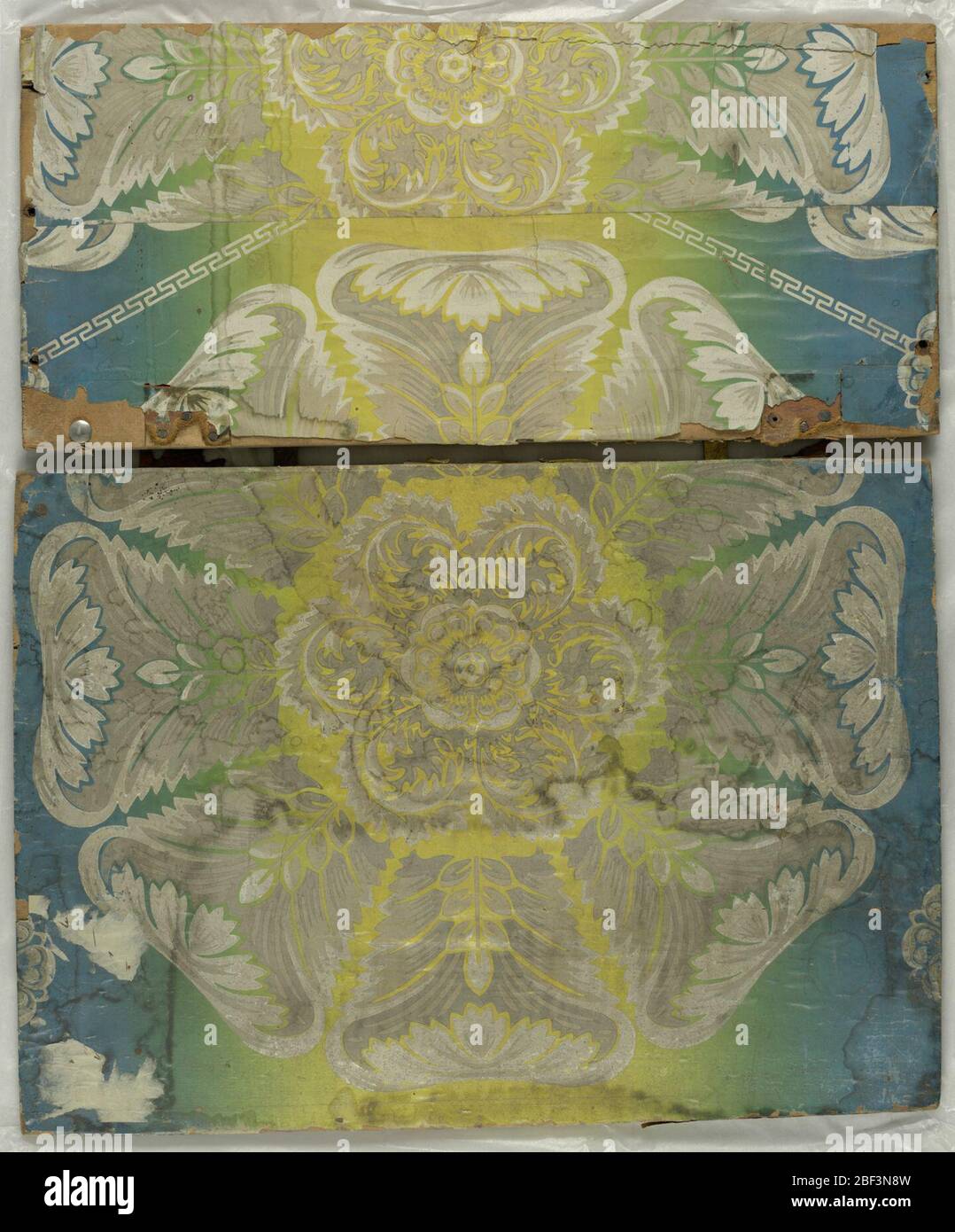 Flanc. Une rosace ou un médaillon d'acanthus à grande échelle avec huit branches foliaires. La rosette est imprimée en grisaille sur un fond irisé ou arc-en-ciel qui s'abat du bleu au jaune. Banque D'Images