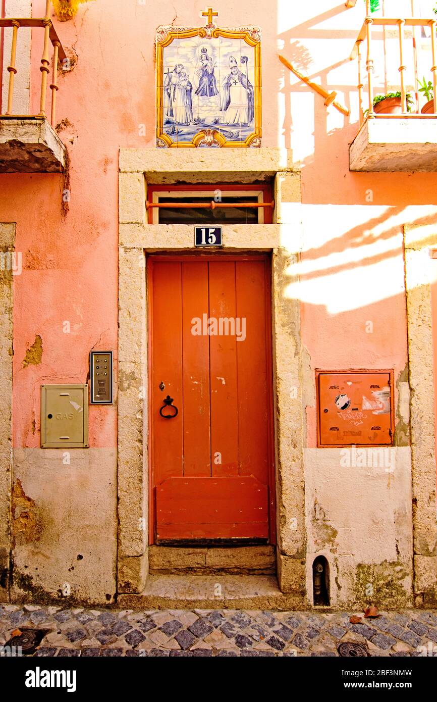 Les tuiles azulejo représentant des saints au-dessus d'une porte orange dans le quartier d'Alfama à Lisbonne Banque D'Images
