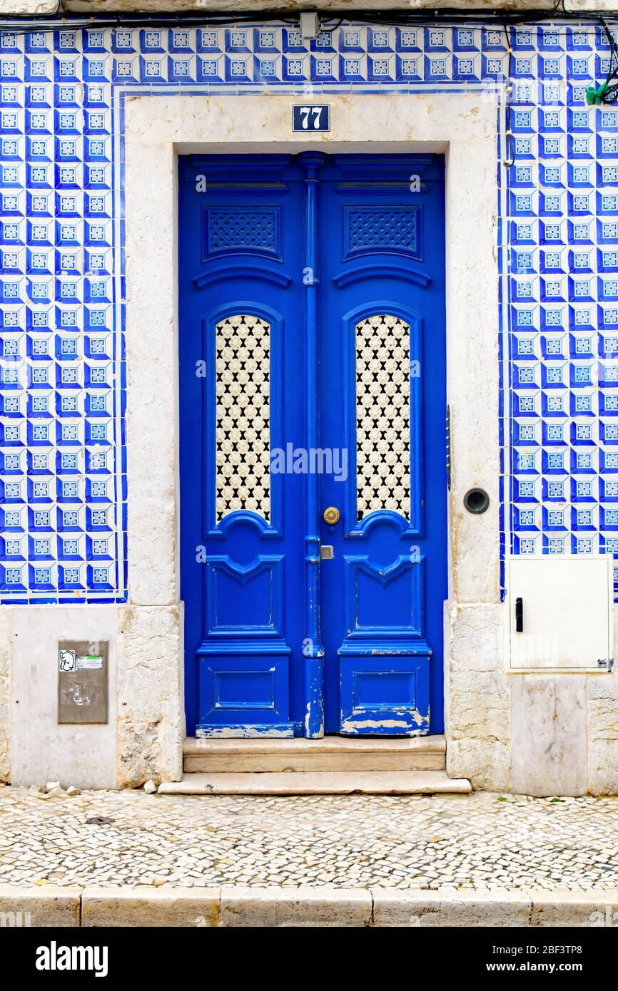 Porte bleue classique ornée dans un bâtiment avec des carreaux azulejo bleus géométriques Banque D'Images