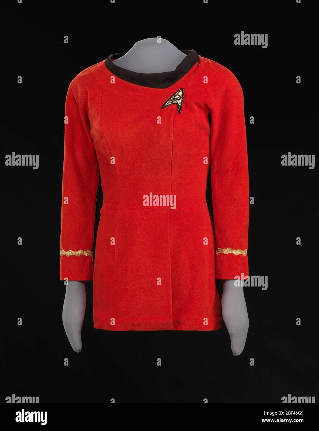 Uniforme Red Starfleet porté par Nichelle Nichols comme Lt Uhura sur Star Trek. Ce uniforme rouge Starfleet a été porté par Nichelle Nichols comme le personnage Lt. Uhura à la télévision Star Trek. La mini-robe rouge est fabriquée en tissu velours synthétique avec des détails dorés et un col en maille noire. Banque D'Images