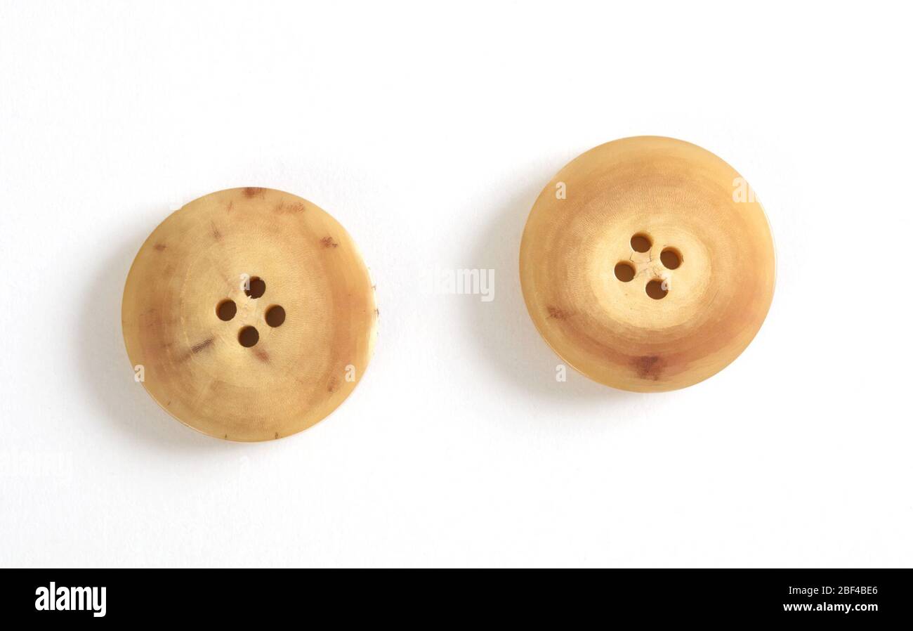Boutons. Deux boutons circulaires beige à brun clair, chacun avec quatre trous. Banque D'Images