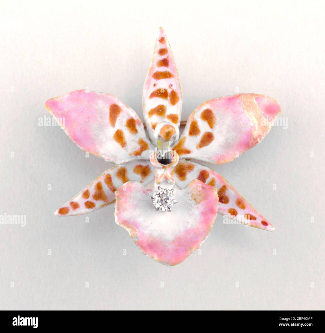 Broche. Broche en or émaillée en forme d'orchidée à six pétales avec strass au centre de la fleur. Banque D'Images