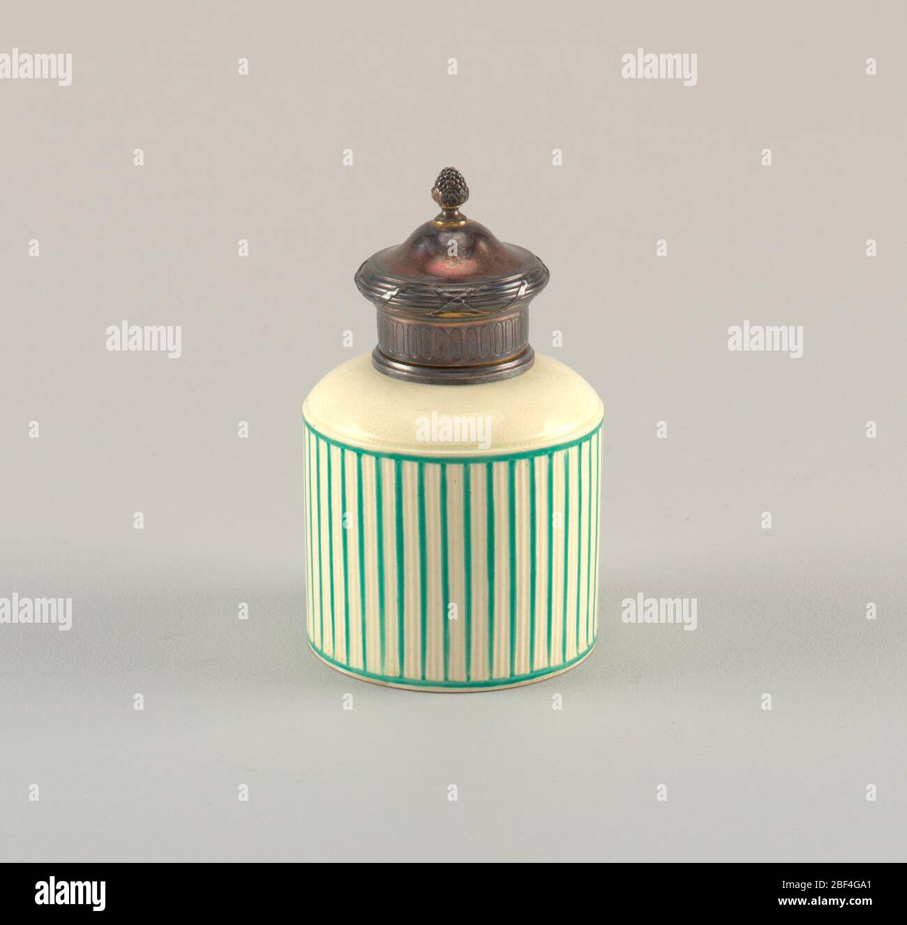 Couvercle. Corps cylindrique. Larges épaules, encolure Snort enchâssée dans un doré argenté. Corps côtelé et rayé en vert. Couverture de doré argenté avec pommeau sous forme de bouquet de raisins. Banque D'Images