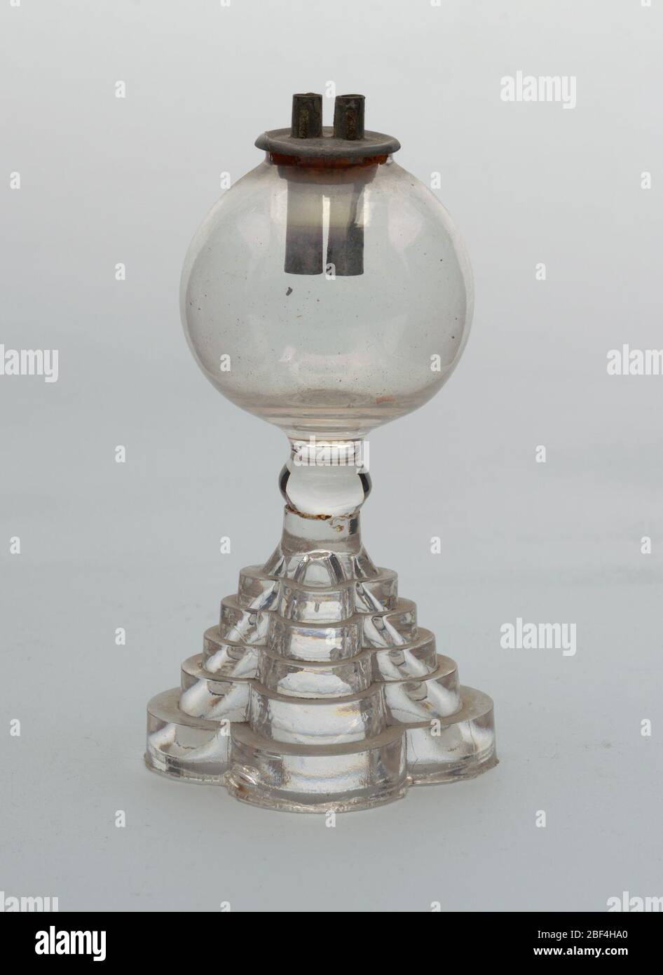 Lampe. Puits de verre soufflé sur des bases étagées (pressées) façonnées en quatre lobes; équipées de deux tubes en boîtes (marquées « BREVET ») avec garniture en liège d'origine. Banque D'Images