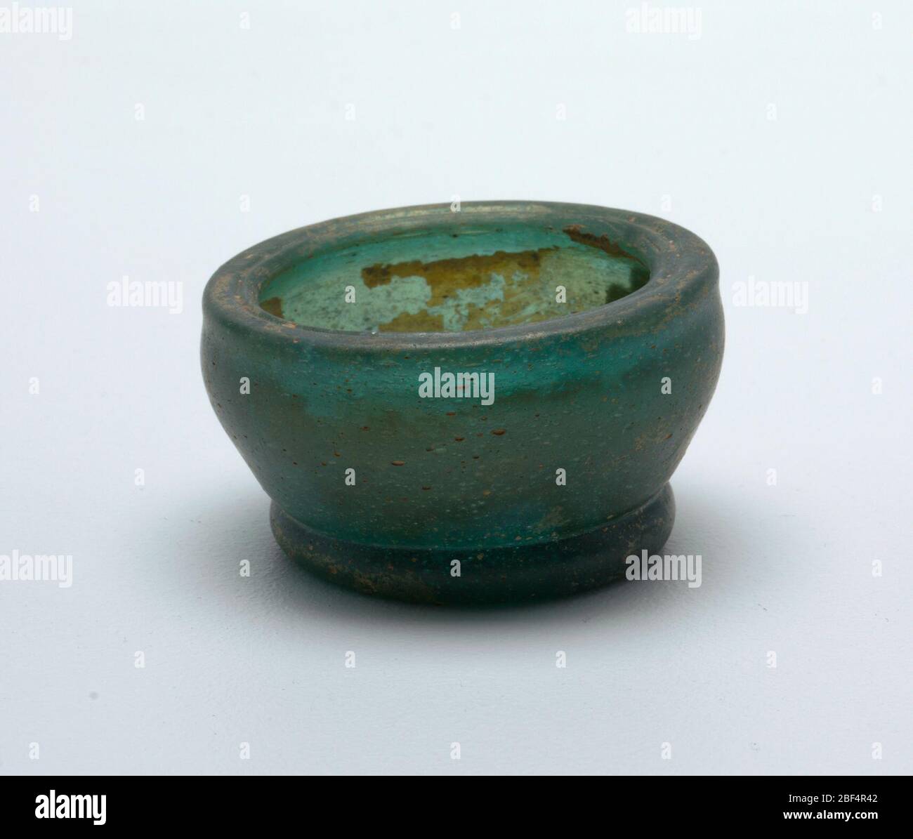 Bol. Verre épais. En forme de cloche, avec lèvre intournée et pied circulaire. Traces d'iridescence. Verre vert foncé Banque D'Images