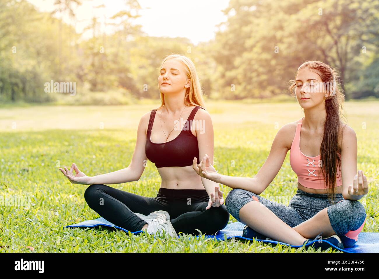 Belles filles teen ami faire le yoga pour la santé dans le parc vert vacances assis main de détente lotus yeux fermé posture de concentration. Banque D'Images