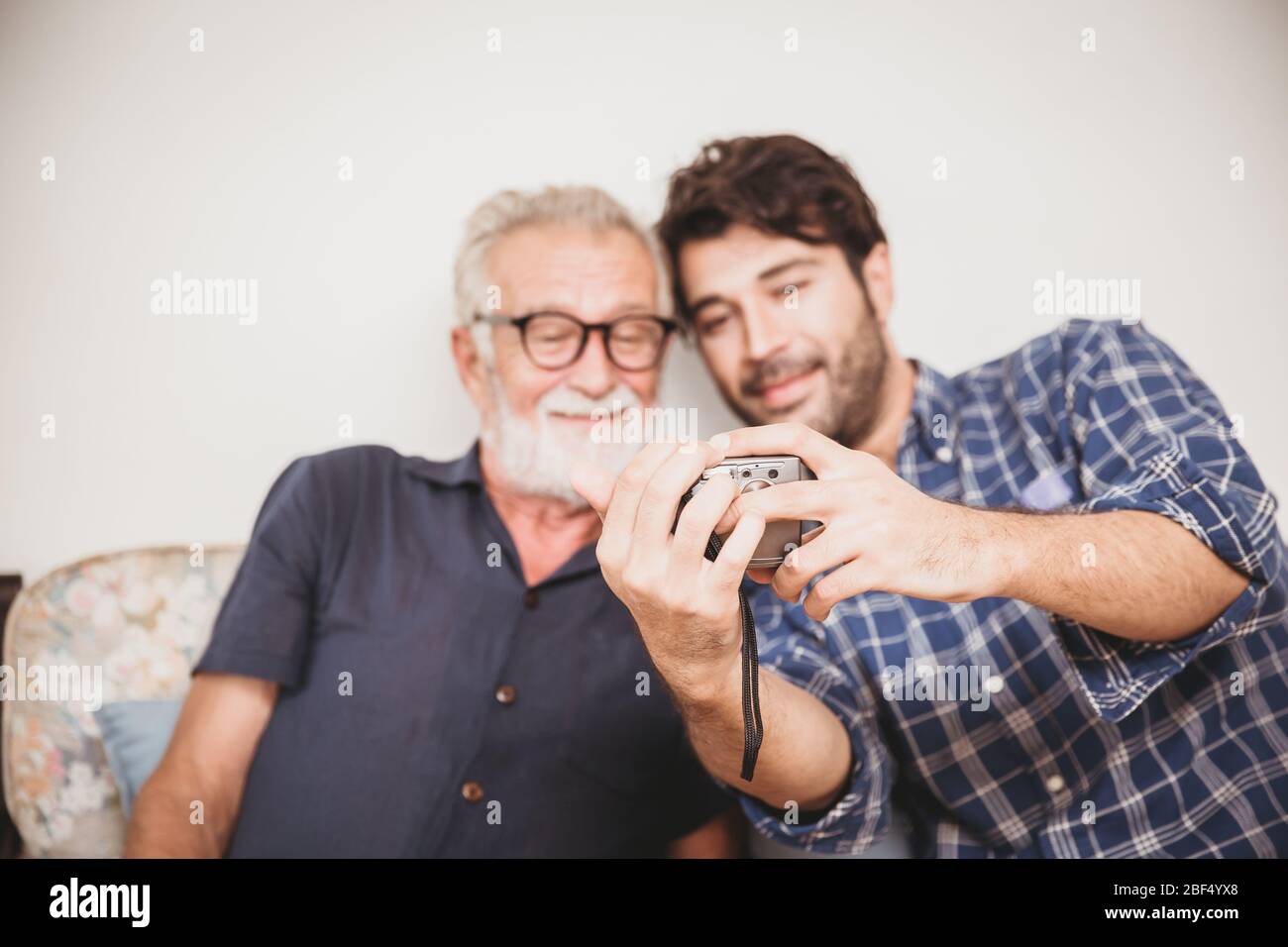 Un aîné regardant rejouer des photos de l'appareil photo numérique avec son fils bonheur famille moment avec le concept de dispositif numérique. Banque D'Images