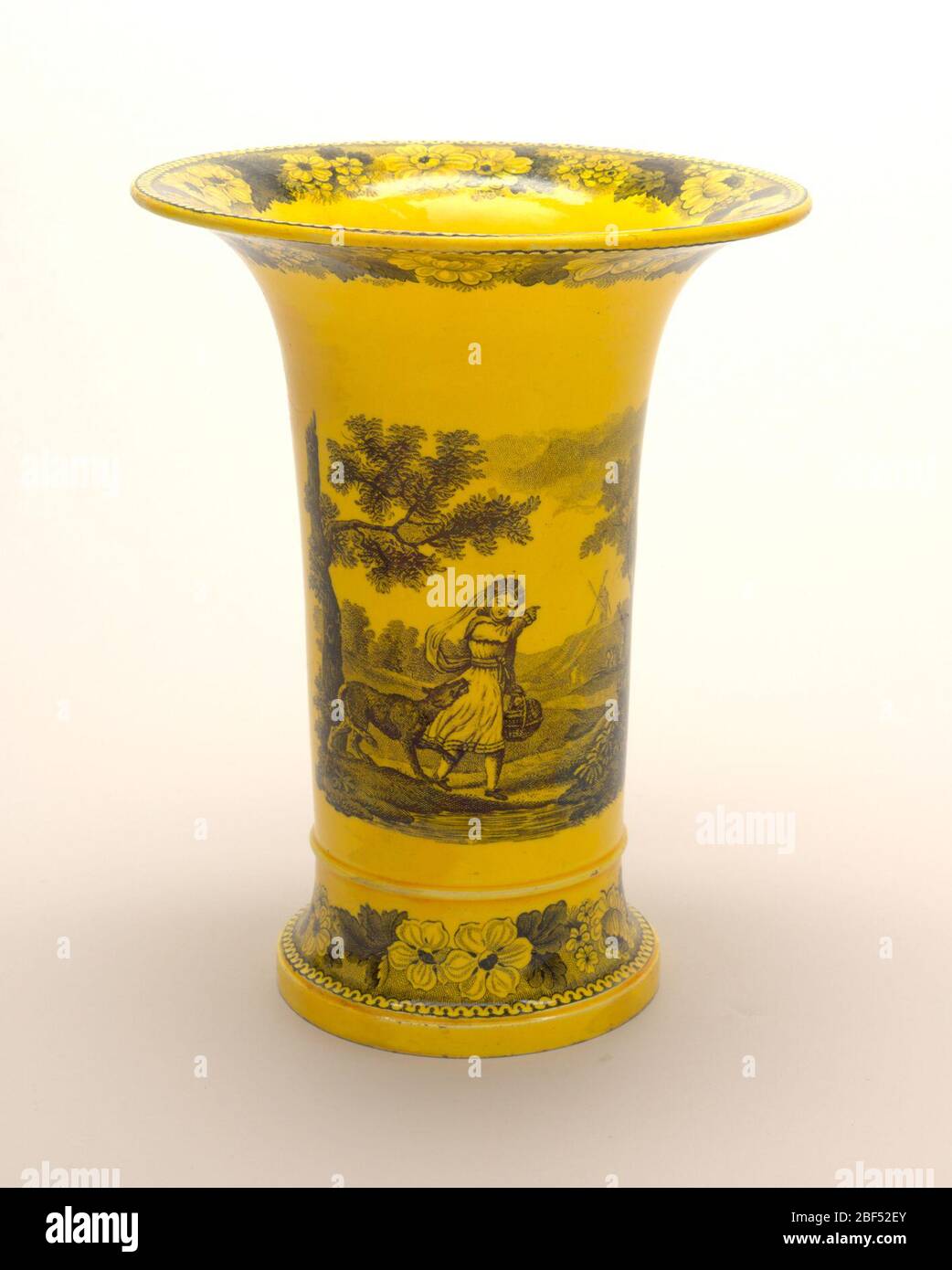 Vase. Vase cylindrique avec bordure évertie; décoration de transféraware noir de la figure dans le paysage sur un sol jaune; bandes de décoration florale sur le bord et la base. Banque D'Images