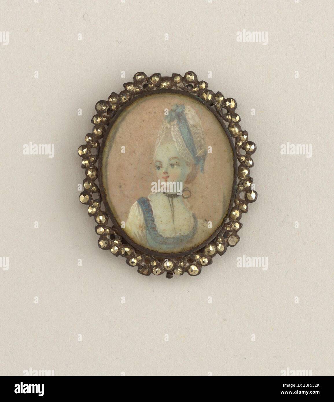Ornement. Portrait miniature d'une dame peinte en aquarelle sur papier et sculptée avec du verre, montée dans un cadre en acier découpés. Sur le dos en haut et en bas se trouve un morceau d'acier incurvé percé de six trous. Banque D'Images