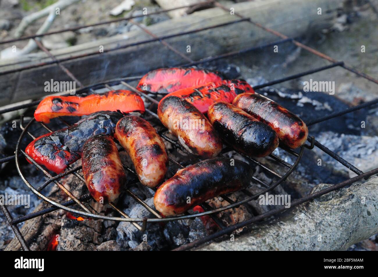 Saucisses et poivrons rouges cuisant au feu de camp Banque D'Images