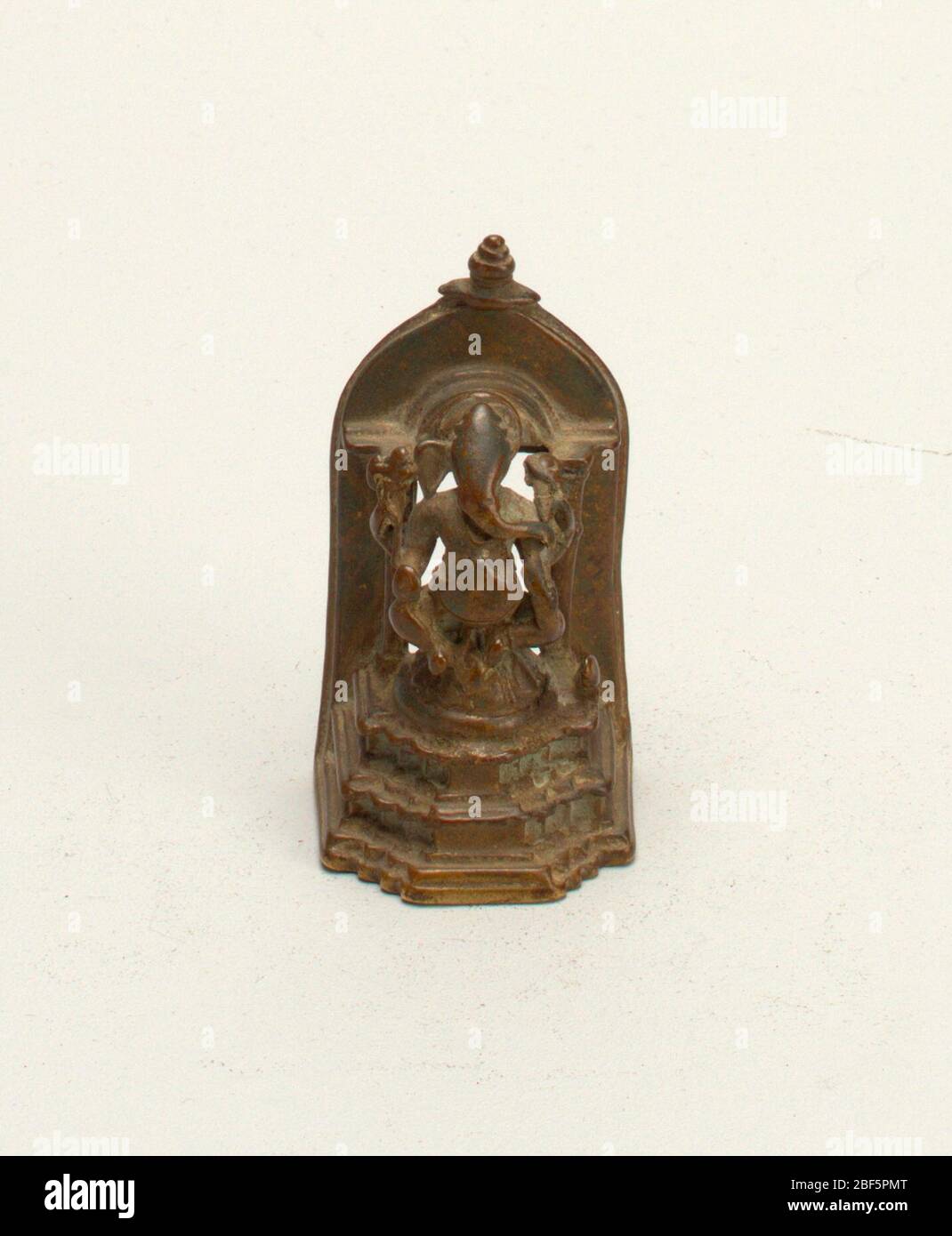 Sanctuaire votif avec figure de Ganesha fourarmé. Ganesha est assis sur un bourgeon fermé de lotus sur un support à trois niveaux devant une niche arqué. Banque D'Images