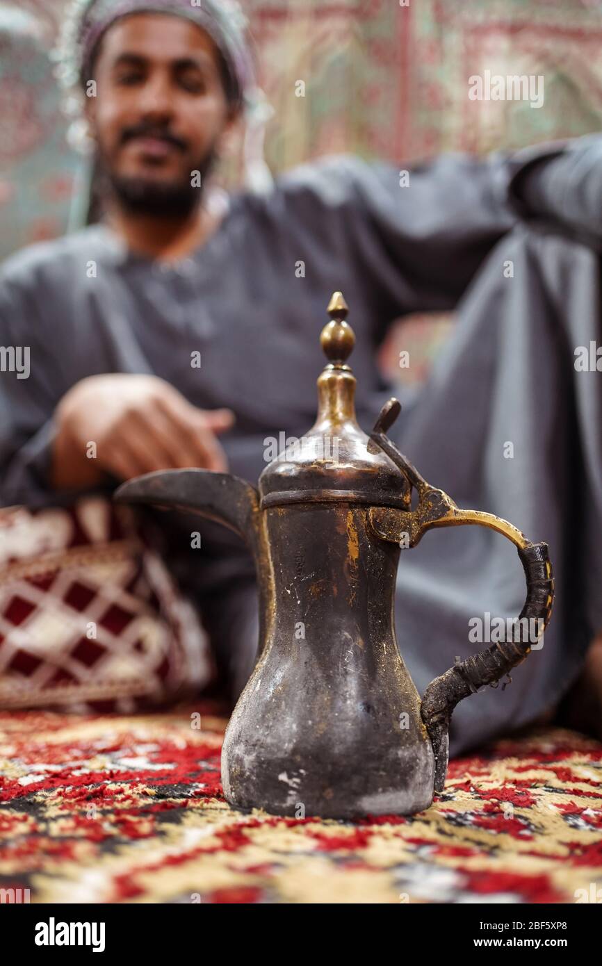 Gros plan sur la théière arabe traditionnelle avec un bédouin portant des vêtements traditionnels assis sur un tapis dans le désert saoudien, en Arabie Saoudite Banque D'Images