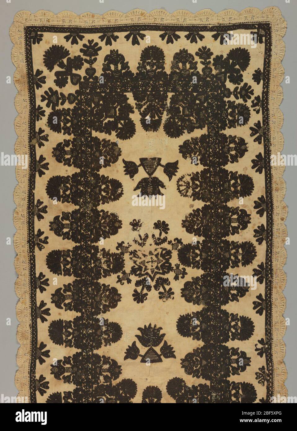 Panneau. Un panneau rectangulaire, probablement un tapis All Souls Day, de linge tissé main de couleur crème, brodé en laine noire. Bordure avec dentelle à aiguille en lin crème. Le motif est un motif central en forme d'étoile entouré de formes florales stylisées. Banque D'Images