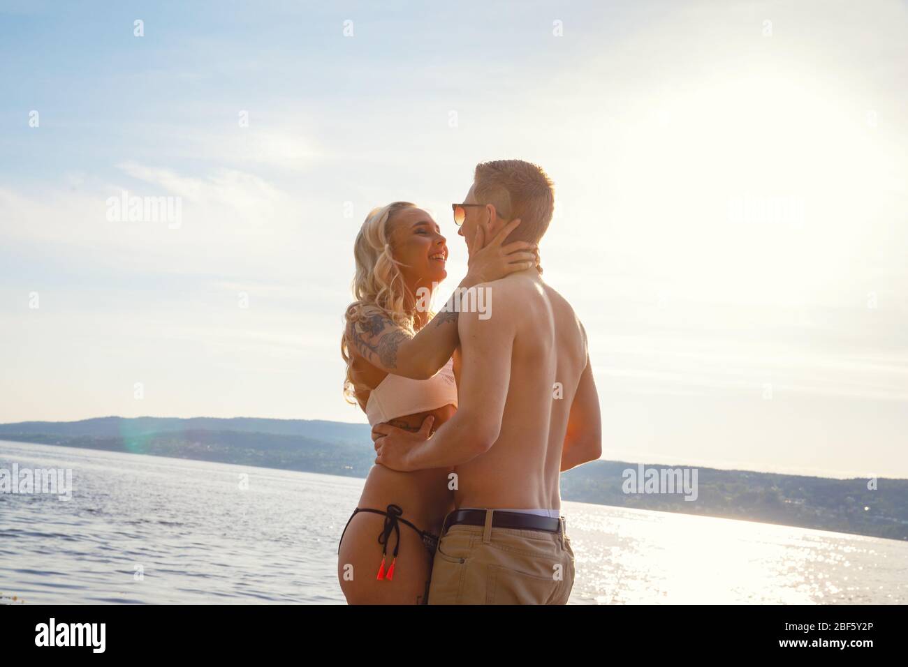 Heureux rire couple en amour riant de la plage contre le soleil Banque D'Images