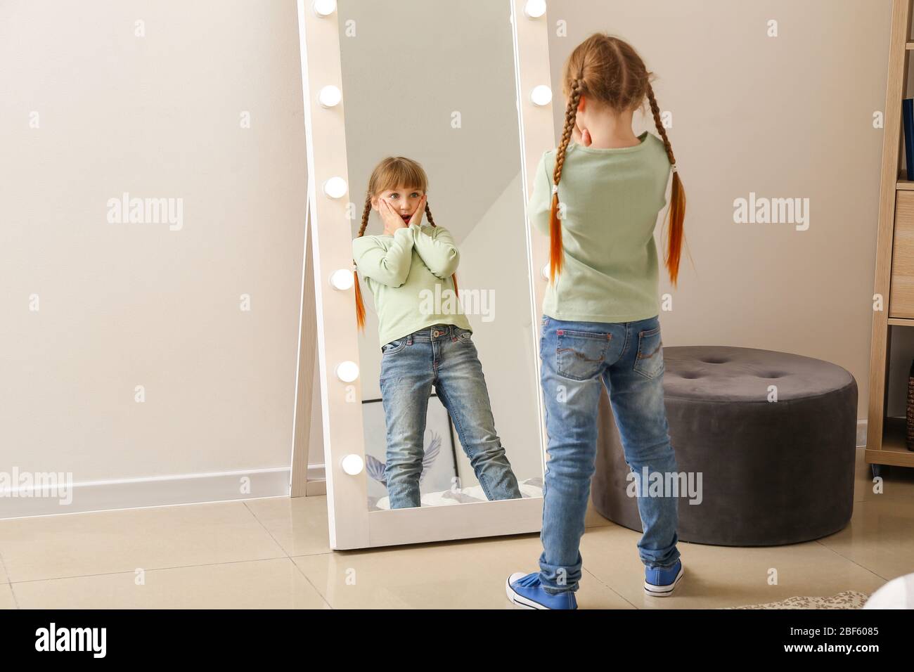 Une petite fille surprise regardant dans le miroir à la maison Photo Stock  - Alamy