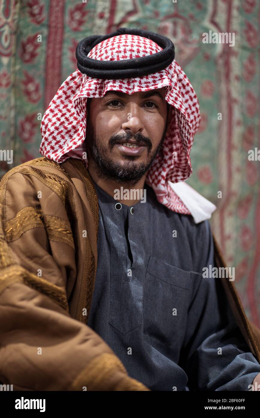 Portrait d'un bédouin portant un foulard traditionnel assis sur un tapis dans le désert saoudien, en Arabie Saoudite Banque D'Images