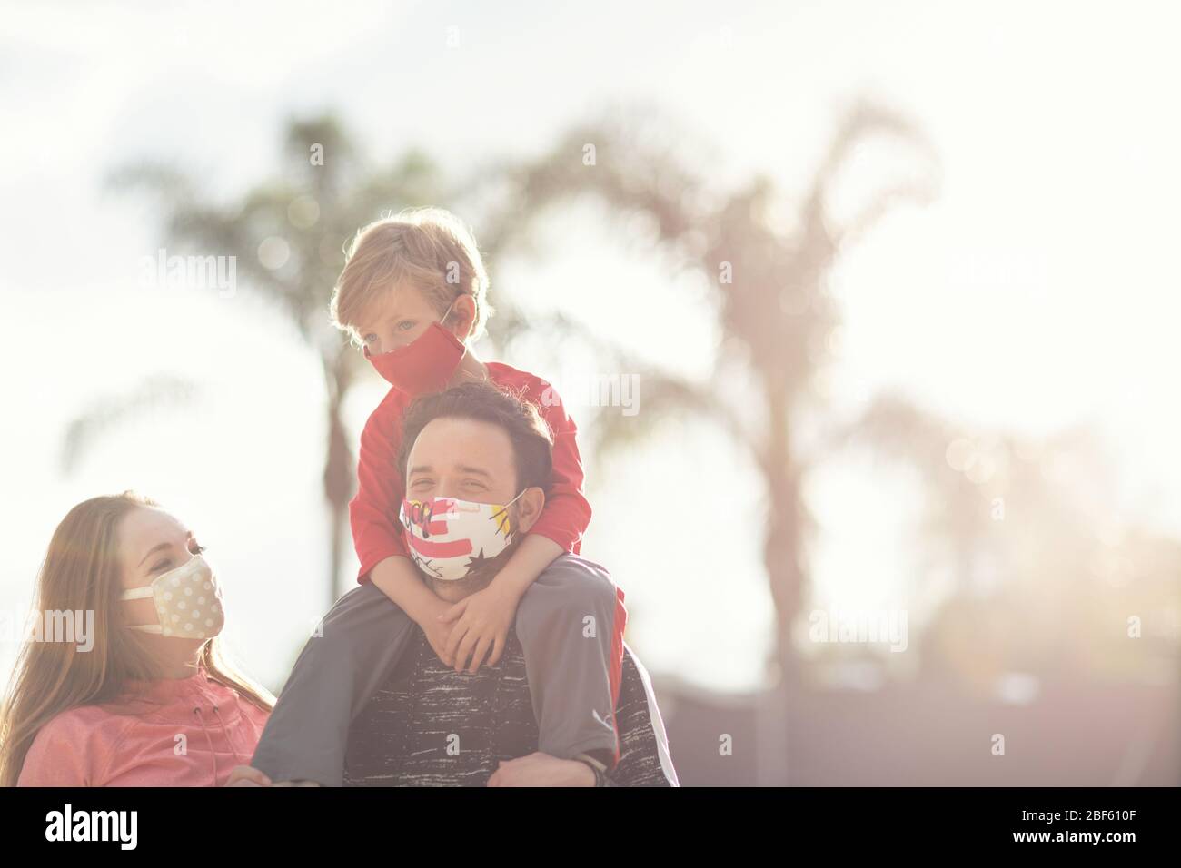 Un jeune couple de famille et leur fils marchant portent des masques de visage en tissu. De nombreux pays recommandent aux citoyens de couvrir leurs visages pendant le coronavirus mondial Banque D'Images
