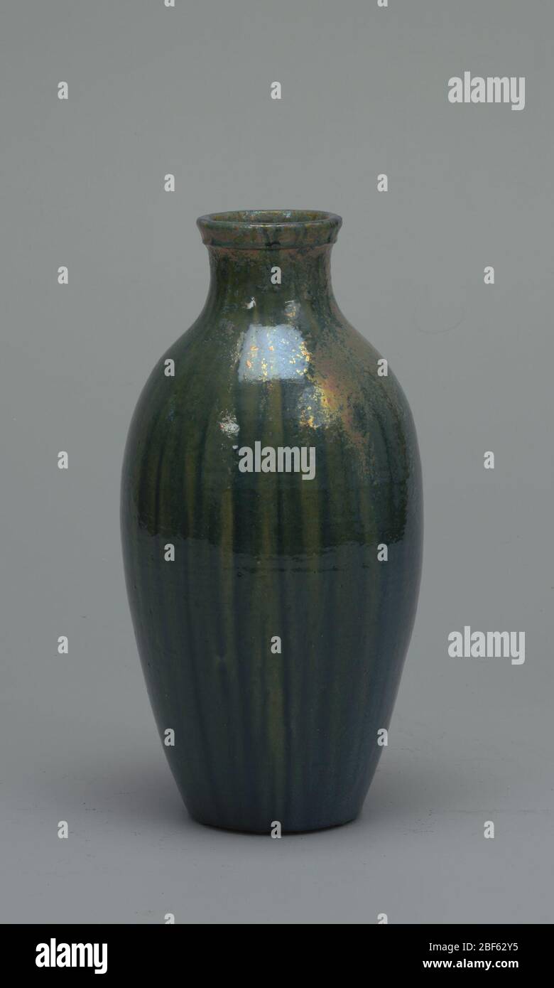 Vase. Corps en argile de buff, jeté. Corps ovoïde avec col incurvant et bord moulé ; pas de pied. Épaisse couche de bleu-vert intense sur toute la surface avec stries de jaune-vert. Irisence lustre or et violet à l'épaule et au cou. Intérieur vitré. Légère observation de la glace. Banque D'Images