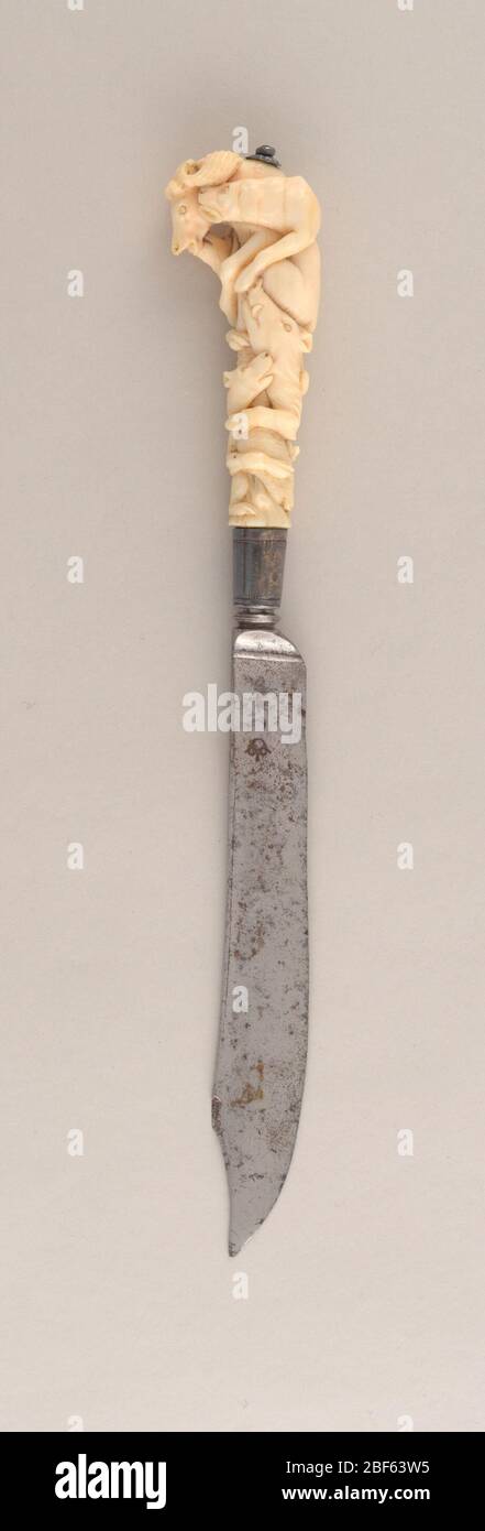 Couteau. Lame en forme de Scimitar, pointe incurvée de pointe tournée. Encolure satinée, ferrule argentée avec bordure gravée. Poignée ivoire sculptée en relief avec des chiens de chasse et des proies enchevêtrés : cerf, sanglier, lapin. Capuchon de bouton à l'extrémité de la poignée. Banque D'Images