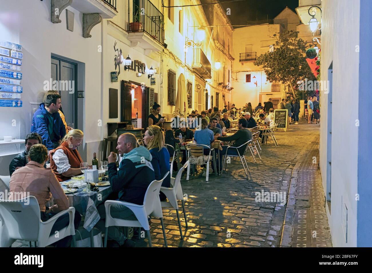 Scène de rue la nuit. Les gens qui dînont dans les restaurants sur le trottoir. Tarifa, Costa de la Luz, province de Cadix, Andalousie, sud de l'Espagne. Banque D'Images