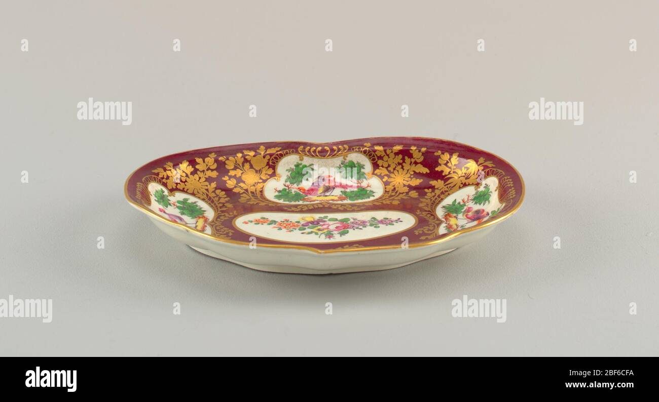 Plat à dessert déchré. Plat en forme de rein. Sol de marron avec réserves blanches remplies d'oiseaux et de fleurs. Décoration fleurie dorée. Banque D'Images