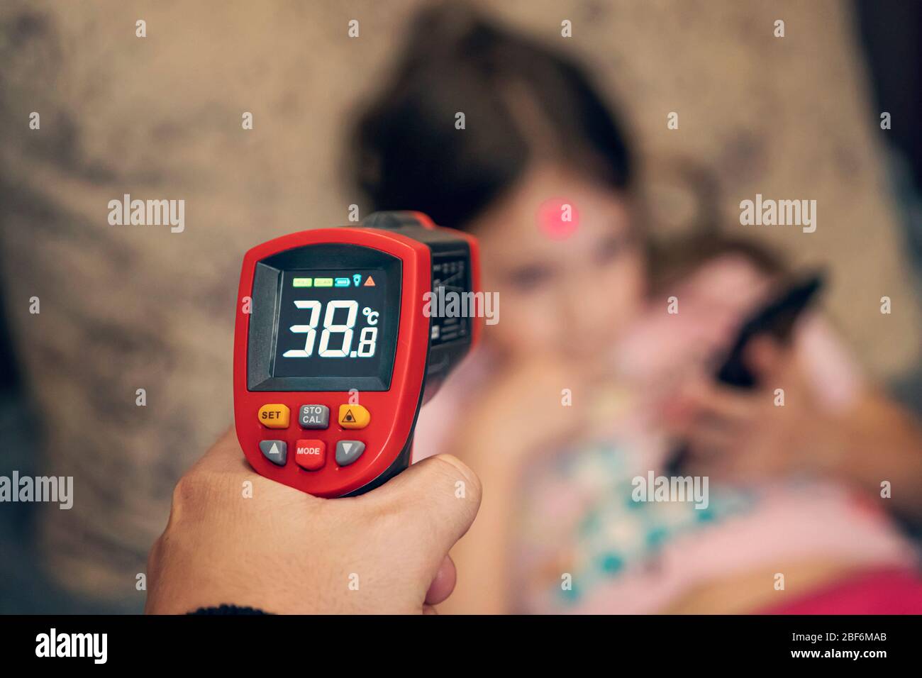 Le thermomètre vérifie la température élevée de la petite fille à distance. Banque D'Images