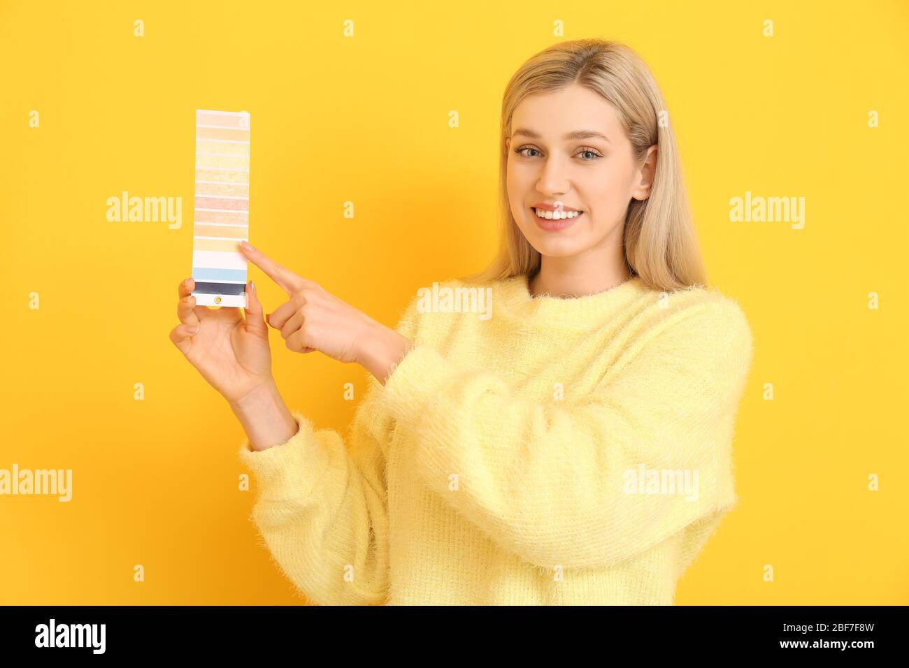 Jeune femme avec palette de peinture sur fond de couleur Banque D'Images