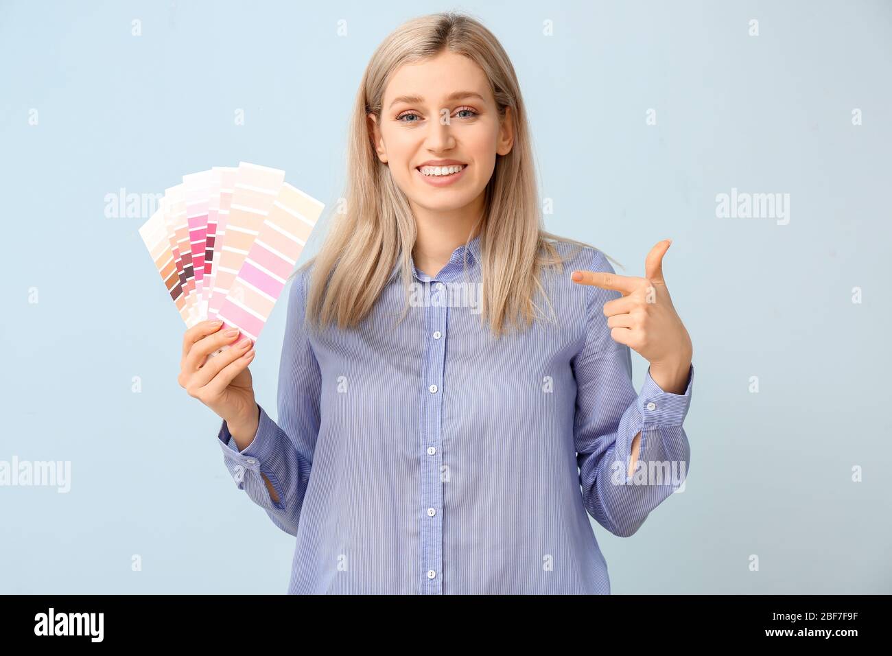 Jeune femme avec palette de peinture sur fond de couleur Banque D'Images