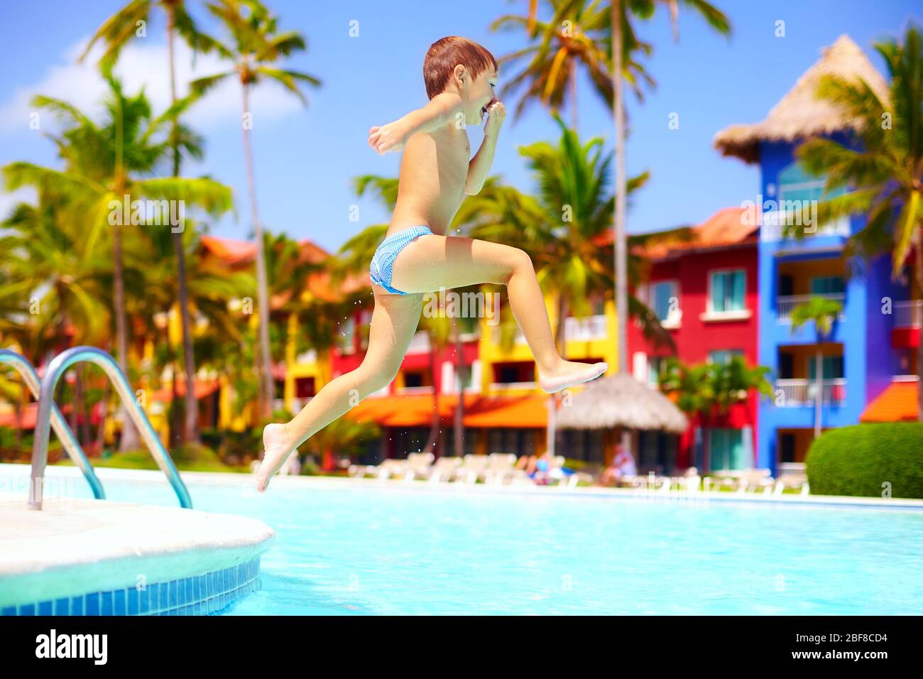 joyeux enfant excité qui sautait dans la piscine en vacances d'été Banque D'Images