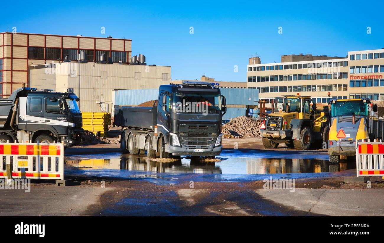 Chariot à benne basculante Volvo noir transportant une charge de gravier quitte le chantier avec des machines lourdes le jour ensoleillé. Helsinki, Finlande. 17 avril 2020. Banque D'Images