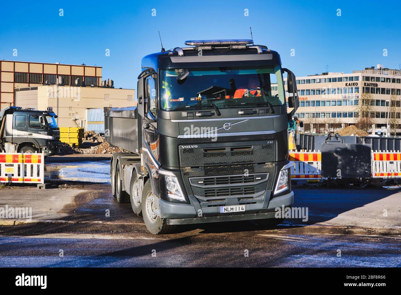 Chariot à benne basculante Volvo noir transportant une charge de gravier quitte le chantier avec des machines lourdes le jour ensoleillé. Helsinki, Finlande. 17 avril 2020. Banque D'Images