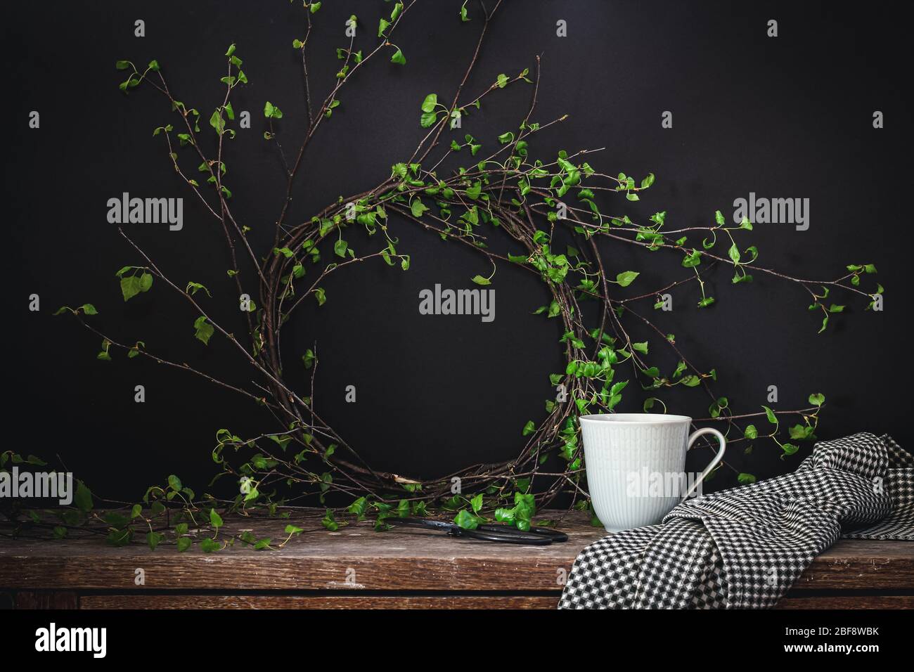 Couronne de printemps faite de jeunes branches de bouleau et une tasse de thé sur fond sombre Banque D'Images