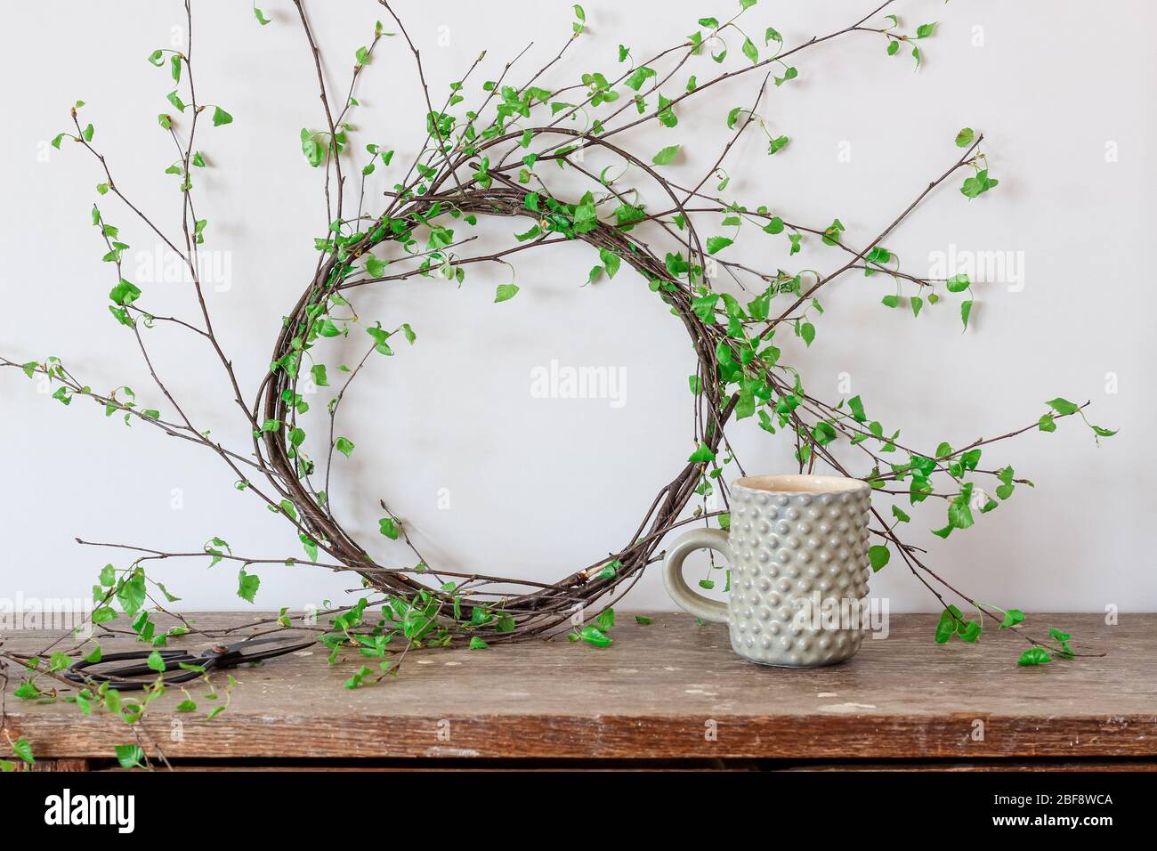 Les branches de bouleau vert couronne et une tasse de thé sur une table rustique Banque D'Images