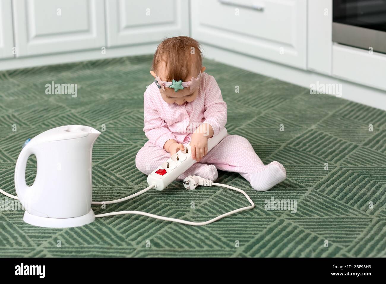 Petit bébé jouant avec rallonge et bouilloire à la maison. Enfant en danger  Photo Stock - Alamy