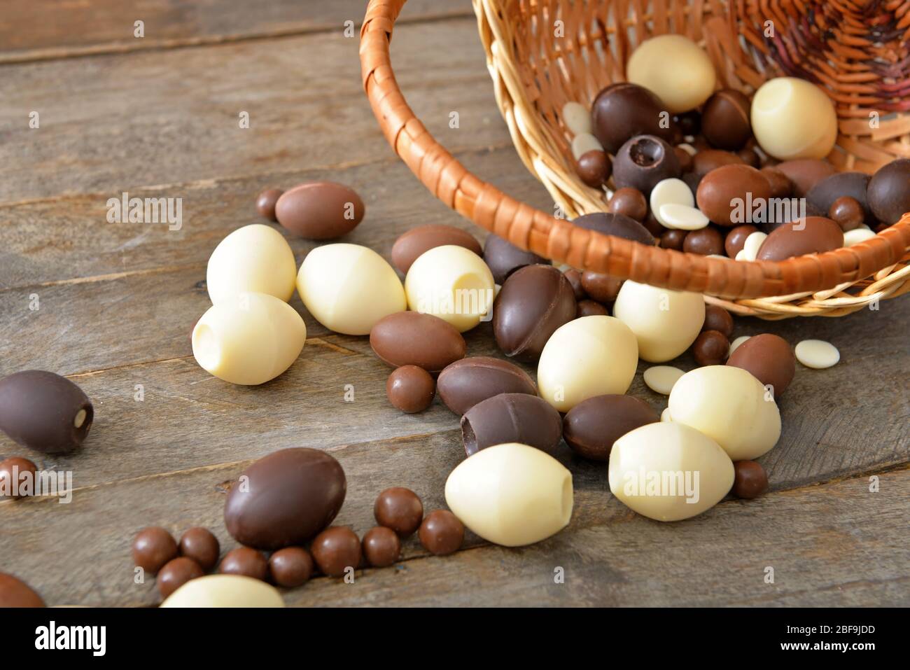 Panier avec œufs et bonbons au chocolat sur table en bois Banque D'Images