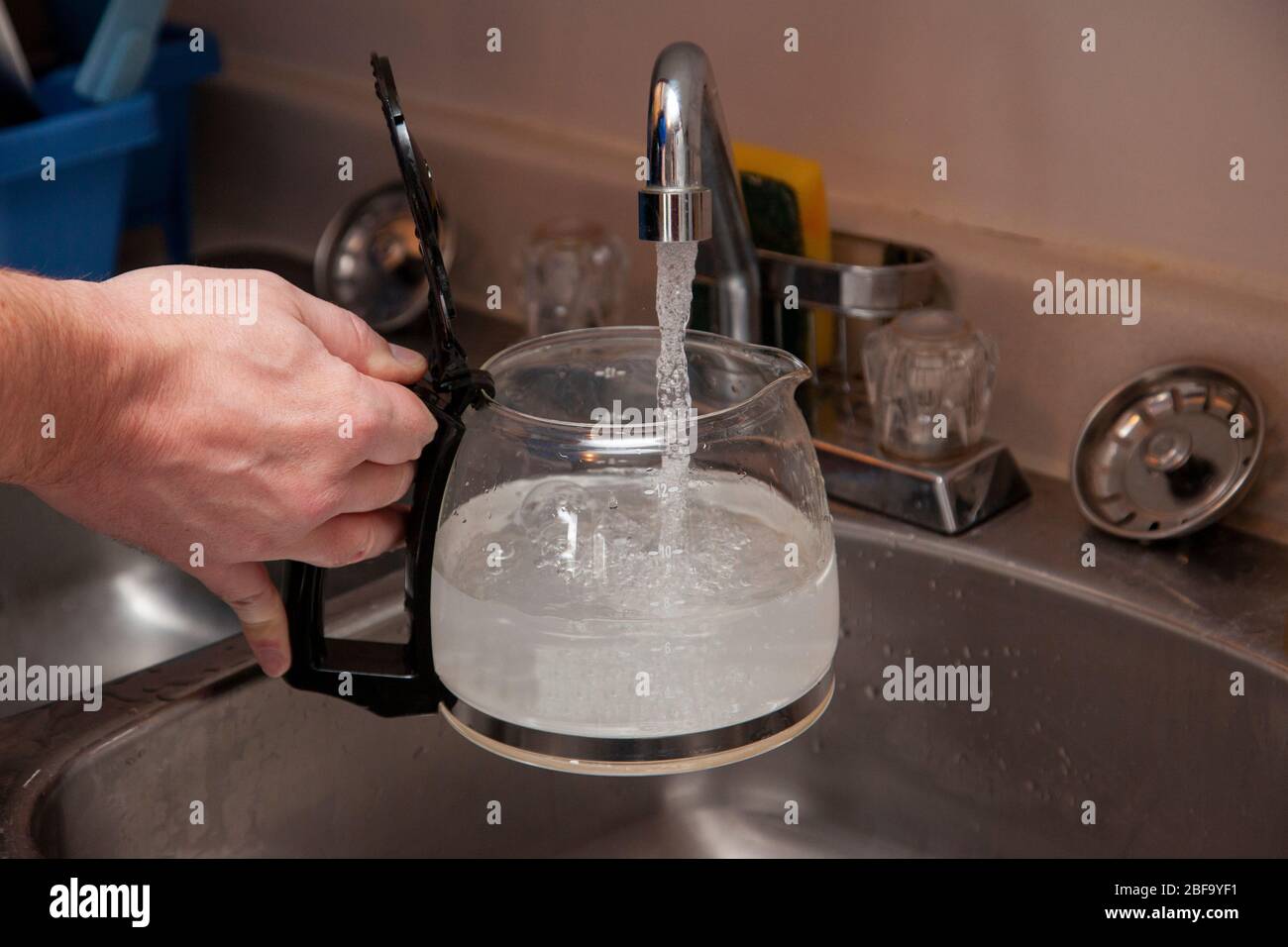 remplissez la cafetière en verre d'eau dans l'évier de la cuisine Banque D'Images