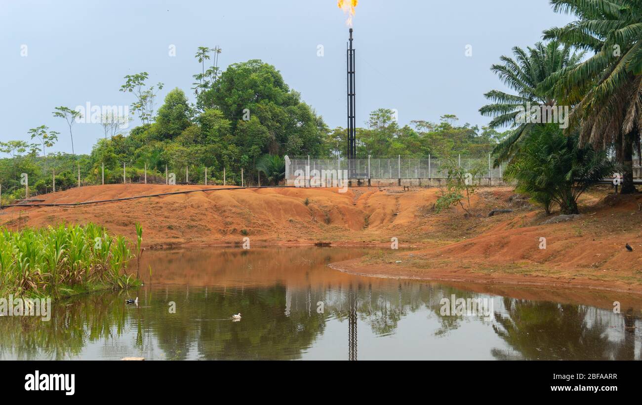 Vue avant d'une production de gaz naturel puits tour brûlant gaz sur le dessus près d'un lagon au milieu de la jungle à Putumayo - Colombie Banque D'Images