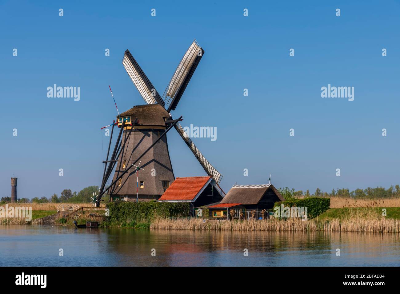 Vue aérienne d'un ancien moulin à vent traditionnel néerlandais sur la campagne rurale des Pays-Bas avec une digue, des canaux, un pont et des champs. Banque D'Images