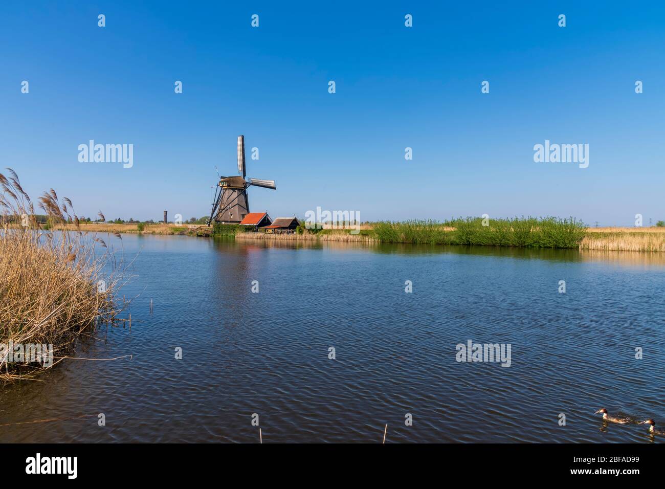 Vue aérienne d'un ancien moulin à vent traditionnel néerlandais sur la campagne rurale des Pays-Bas avec une digue, des canaux, un pont et des champs. Banque D'Images